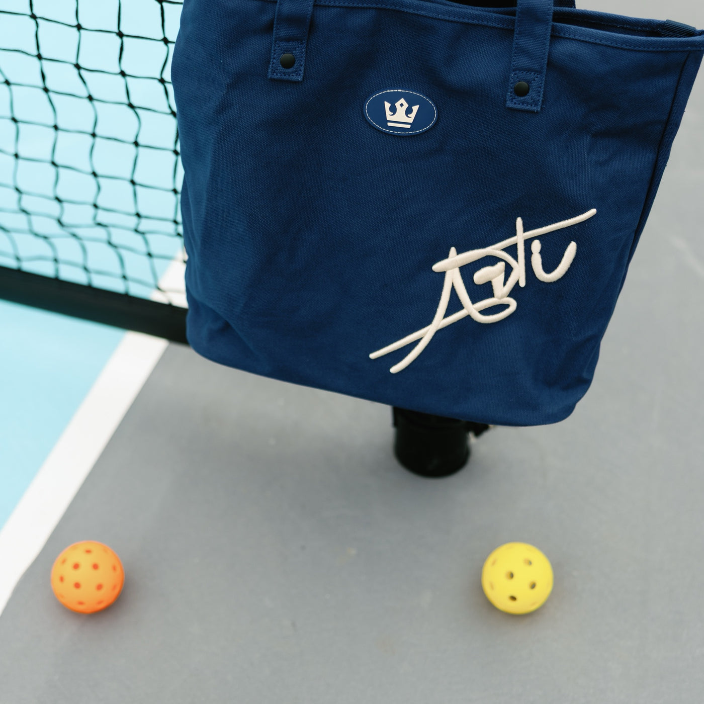 ARTI navy canvas tote bag on a pickleball court with balls
